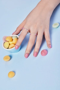 Close-up of rainbow gradient zircon rings on model hand with colorful candy decor