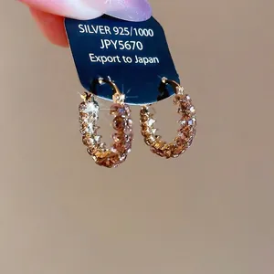 Elegante geometrische Goldohrringe mit Champagner-Zirkonia auf einer Displaykarte