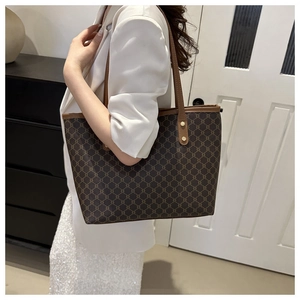 Detail of vintage monogram tote bag with leather handles shown on a white blazer model