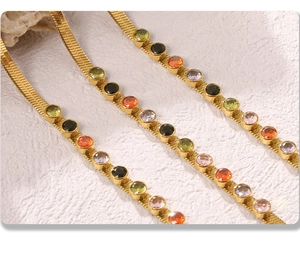 Macro shot of 18k gold plated flat snake chain necklaces with colorful round zircons