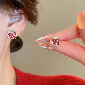 Gros plan de boucles d oreilles en perles avec de petits nœuds rouges sur l oreille