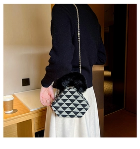 Detail of a geometric triangular wrist bag with woven texture and faux fur handle trim