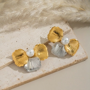Elegant two-tone flower stud earrings with white pearl center on a beige stone surface