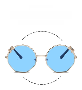 Détail de lunettes de soleil enfants polygonales dorées avec verres bleus et nœud brillant