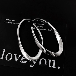 Minimalist silver oval hoop earrings with high-polish metallic finish on black background