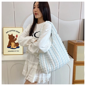 Model wearing a light blue and white ruched shoulder bag with bubble texture in a home setting