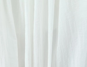 Nahaufnahme von weißem, halbtransparentem Spitzenstoff mit feiner Textur und weichem Fall