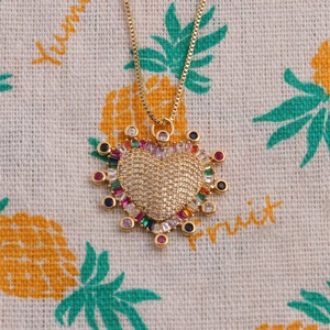 Collier cœur vintage avec zircons colorés sur fond de tissu à motif d'ananas