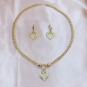Golden stainless steel jewelry set with heart pendants on elegant pink silk background