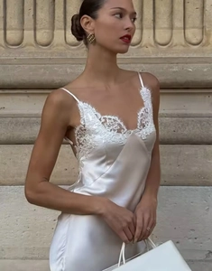 Detail of white satin dress with lace patchwork and slim spaghetti straps