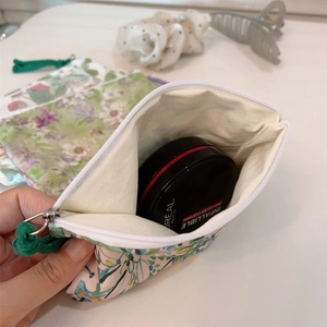 Detail showing a floral cotton pouch holding cushions on a minimalist white desk