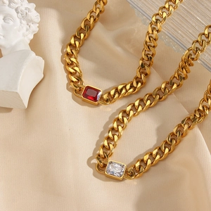Detail of gold Cuban chain necklaces with square ruby and white zircon pendants on silk