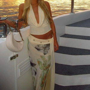 Detail of slit floral maxi skirt with halter top and white crescent chain handbag