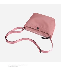 Detailed front view of pink nylon crossbody bag with adjustable strap and front pocket