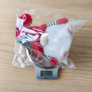 Detailed weight measurement showing light-up Christmas gnome plush at 100.3g on scale
