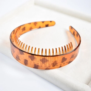 Macro view of leopard print plastic headband with teeth on a beige jewelry tray