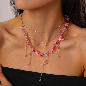 Detail of layered silver necklace with resin flowers and orange beads on model
