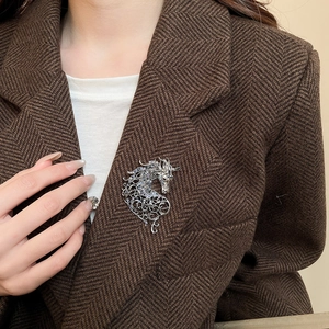 Detailed shot of a silver horse brooch with sparkling crystals on a brown suit lapel