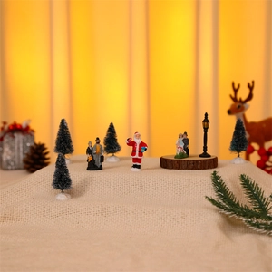 Close-up of miniature Christmas village set with Santa figurines on rustic burlap base