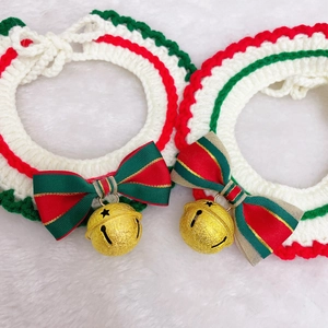 Macro detail of hand-knitted Christmas pet collar with a golden bell and festive red bow