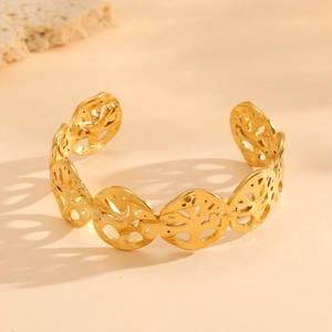 Detailed close-up of a gold hollow tree of life bangle with intricate shadow patterns