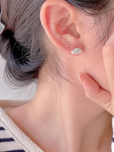 Close-up of minimalist silver shell earrings worn by a model for a chic look
