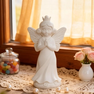 Detail of white praying angel statue with crown and floral relief on a cozy window sill