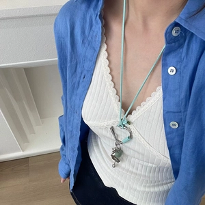 Détail du fermoir cœur et pendentif en pierre sur un collier en coton turquoise