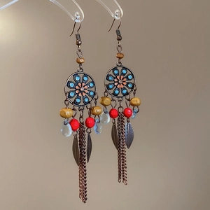 Detail of ethnic fish-style shell tassel earrings with bronze floral accents and colorful beads