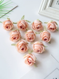 Flat lay of ten soft pink silk artificial rose heads for DIY handmade crafts decor