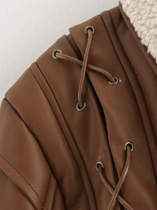 Détail d'une veste en cuir marron avec bordure en peau de mouton et design à lacets