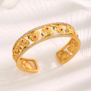 Vintage gold-plated cuff bracelet featuring embossed roses with red and green stones