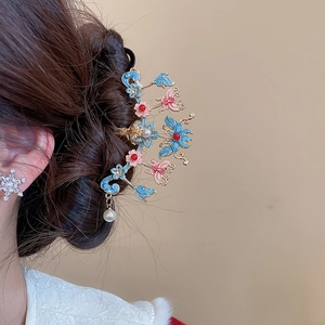 Détail d'un pic à cheveux doré avec fleurs en émail bleu et pendentif en perle blanche