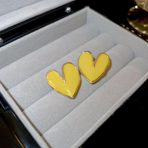 Gros plan sur des boucles d'oreilles cœur en émail jaune et bordure dorée sur velours