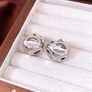 Minimalist silver circular pleated stud earrings with liquid metal texture on white fabric