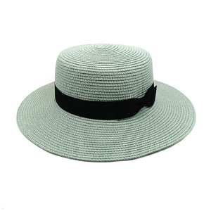 Detail of mint green straw sun hat featuring intricate woven texture and black satin ribbon