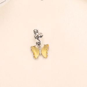 Macro shot of a yellow faceted crystal butterfly pendant with spiral silver metal hair ring