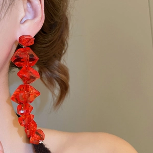 Macro side view of red multi-layered faceted acrylic bead drop earrings worn by a model