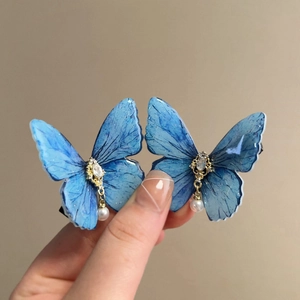 Close-up of blue butterfly hair clips with sparkling rhinestones and white pearl pendants