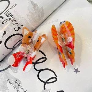 Detail view of fox-shaped acrylic hair claws with winter snowflake patterns on a magazine