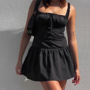 Detail view of black ruffled camisole mini dress with button design and A-line silhouette
