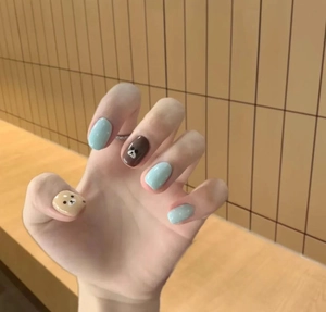 Detail of press-on nails with blue and brown cartoon bear and polka dot patterns