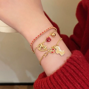 Detailed view of red cord bracelets with golden horse and heart charms for women