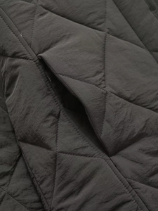 Close-up of black quilted jacket showing detailed diamond stitching and pocket craftsmanship