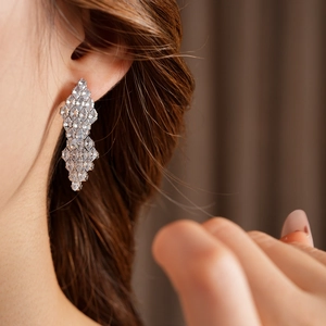 Detailed close-up of a model wearing sparkling cubic zirconia geometric drop earrings