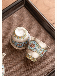 Macro detail of cloisonne enamel teacup with intricate floral patterns on silver base