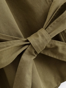 Close-up of military green twill fabric with decorative waist belt knot detail
