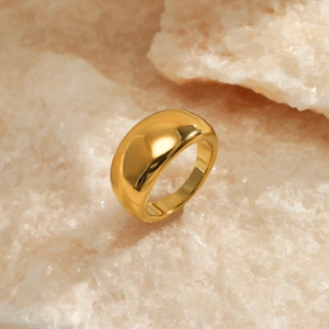 Polished gold plated stainless steel dome ring displayed on a natural stone surface