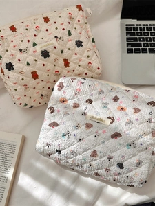 Quilted cartoon makeup bags with puppy and bear prints on a soft fabric surface