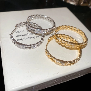 Macro shot of 18k gold and silver curb link hoop earrings with paved cubic zirconia details